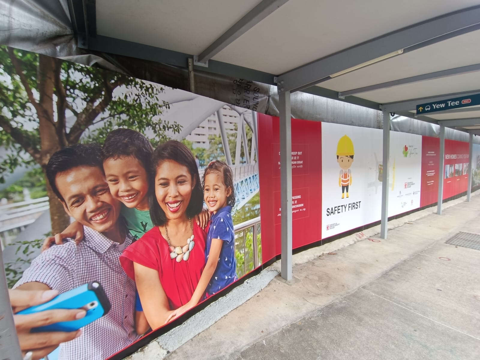 HDB family photo hoarding along a covered walkway — Hoarding Sticker Printing by Garrison Productions, Singapore