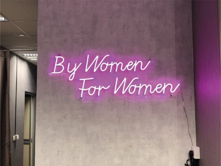 "By Women For Women" neon on a concrete wall — Neon Signs by Garrison Productions, Singapore