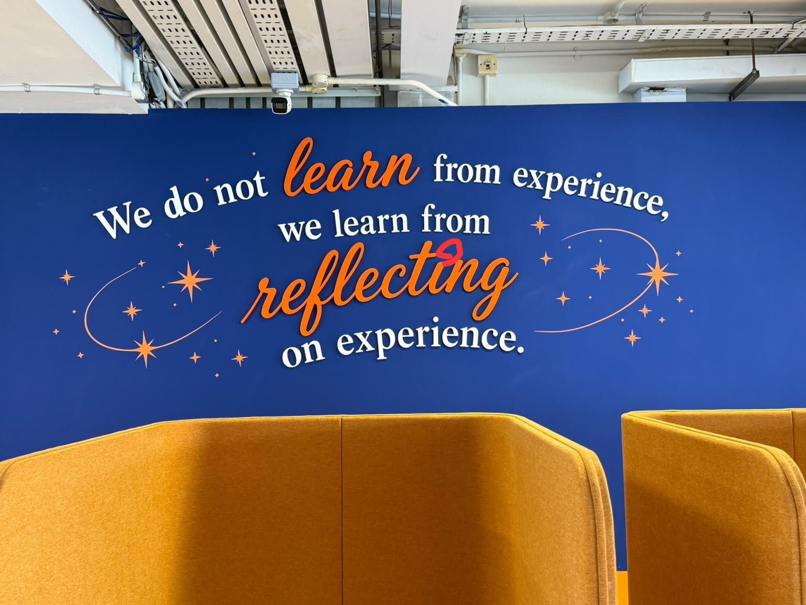 "We learn from reflecting on experience" wall mural behind seating — Wall Mural by Garrison Productions, Singapore