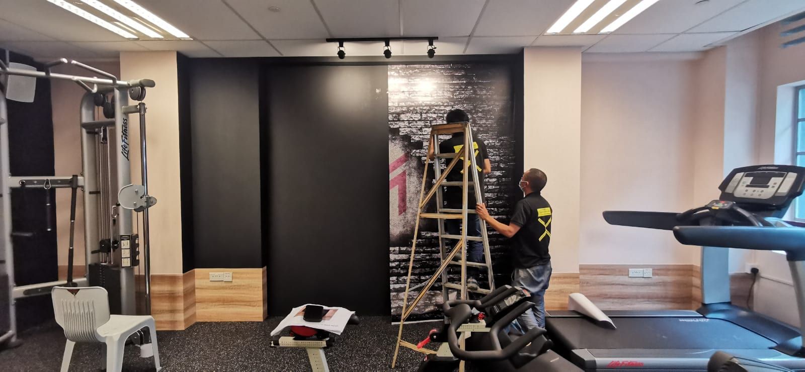 Black wall mural being installed in a gym — Wall Mural by Garrison Productions, Singapore